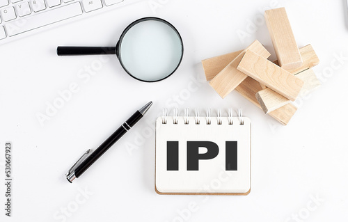 IPI-INDUSTRIAL PRODUCTION INDEX word written on notebook with block magnifier and pen , business concept.