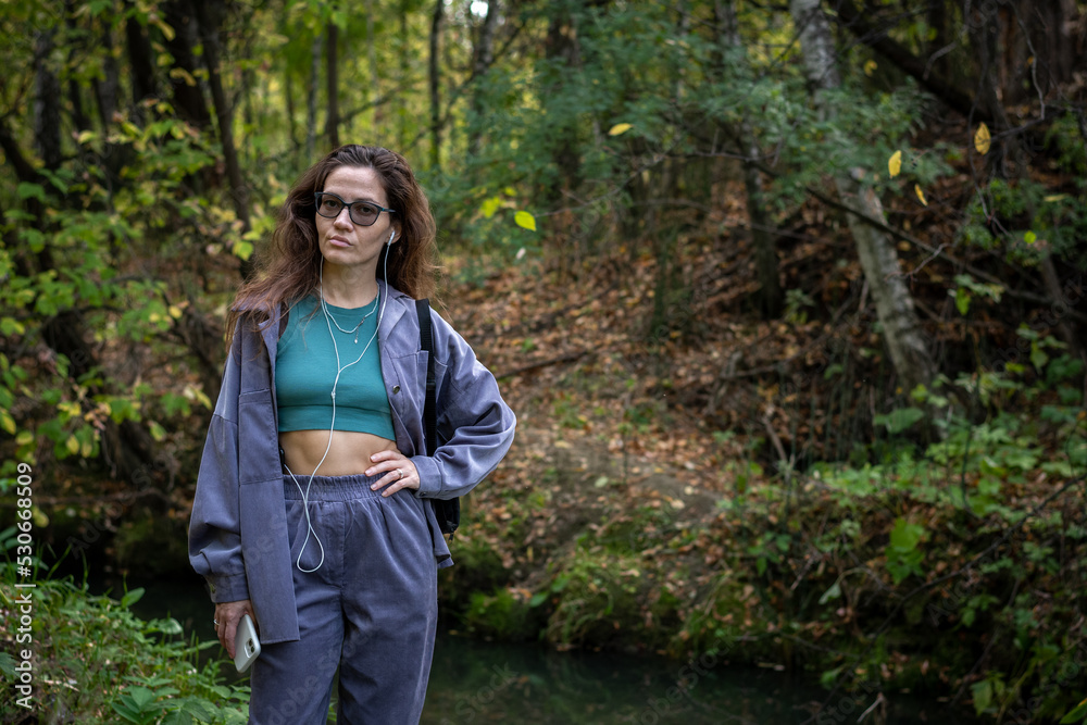 Portrait of romantic woman at fairy forest. A beautiful young girl with glasses is walking through the forest. Girl purple suit. Corduroy fabric Portrait of romantic woman at fairy forest. A beautiful young girl with glasses is walking through the forest. Girl purple suit. Corduroy fabric