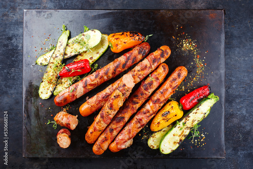 Traditional barbecue Bernese sausage with grilled vegetables served as top view on an old rustic board photo