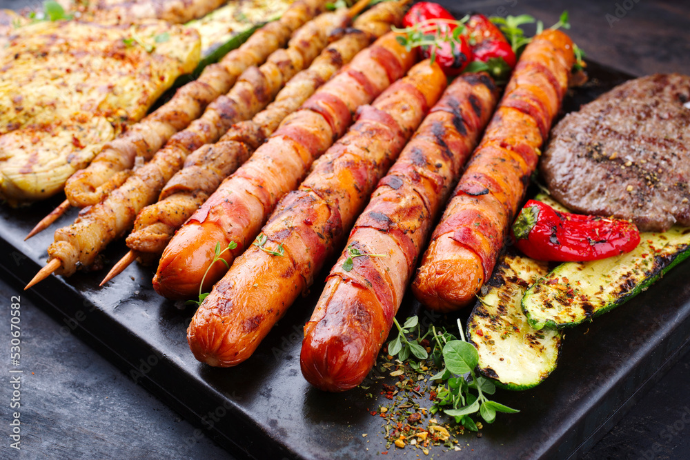 Traditional grill platter with bratwurst, hamburgers and steaks prepared for a summer barbecue served as a close-up on a rustic board Traditional grill platter with bratwurst, hamburgers and steaks prepared for a summer barbecue served as a close-up on a rustic board