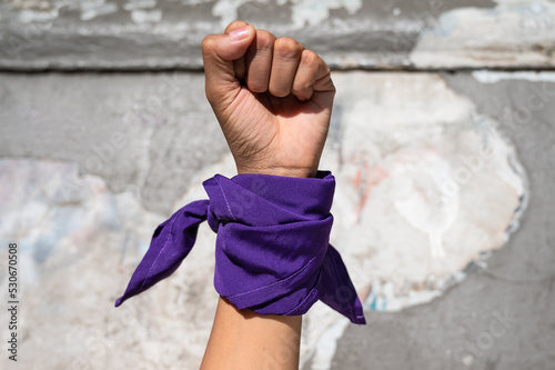 Foto Mano de mujer feminista con pañuelo morado en la calle.