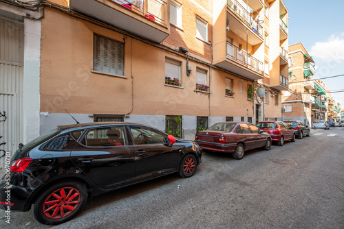 narrow street of a city with parked cars