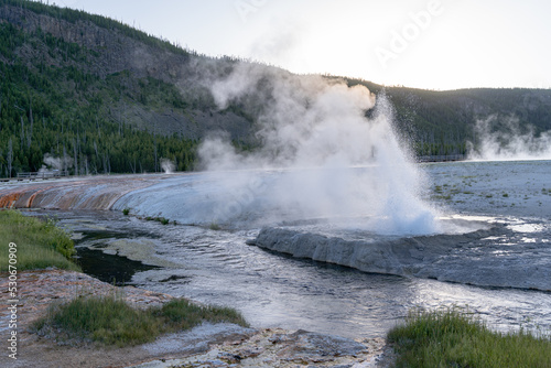 Geyser erupts in the Black Sand Basin area of Yellowstone National Park at sunset