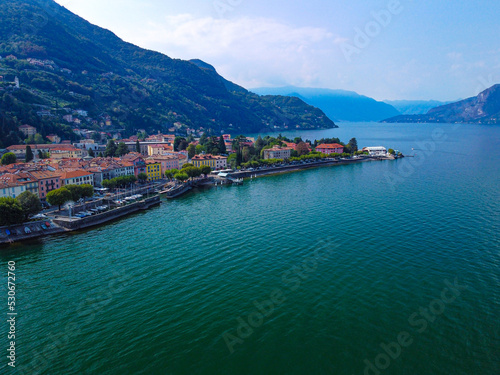 Aerial view of Lake Como. city ​​center. A local ferry arrives in the city. Bell tower. Tourism and romance. Mountains around the lake. Red roofs. Green Planet. Sailing yacht. Italy, Bellano, 09.2022