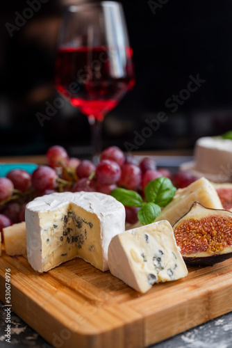 delicious blue brie blue cheese with grapes and figs on a wooden board with a glass of wine