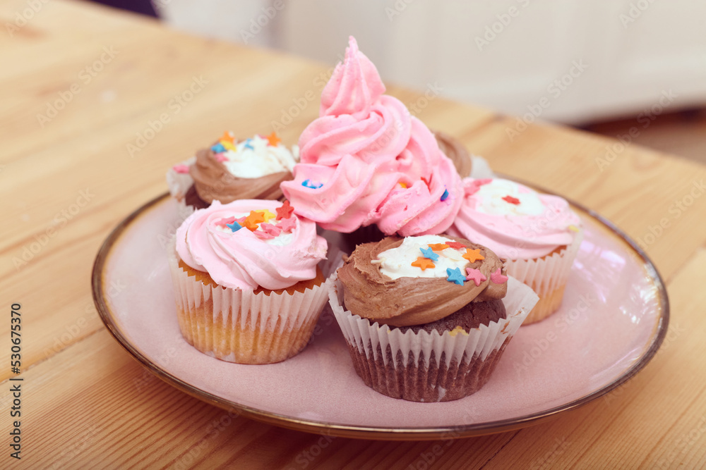 bright cakes with delicate cream on a pink plate stand on a wooden table