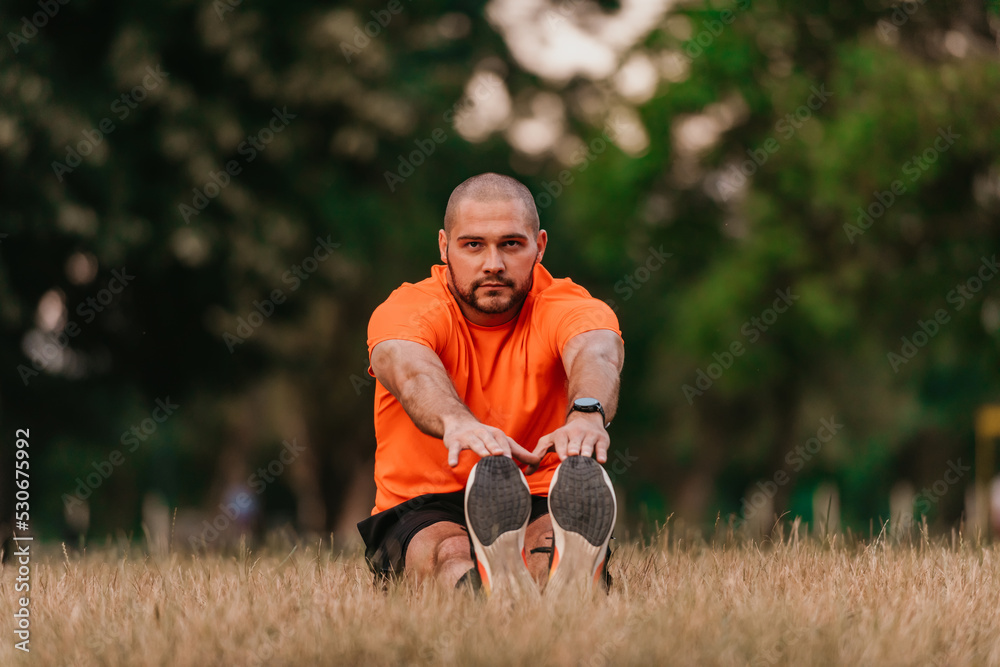 Happy positive sportsman during outdoor workout, man wearing sports outfit warming up muscles,enjoying active lifestyle outside in park