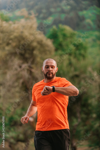 Athlete using a smartwatch while running in nature Healthy lifestyle