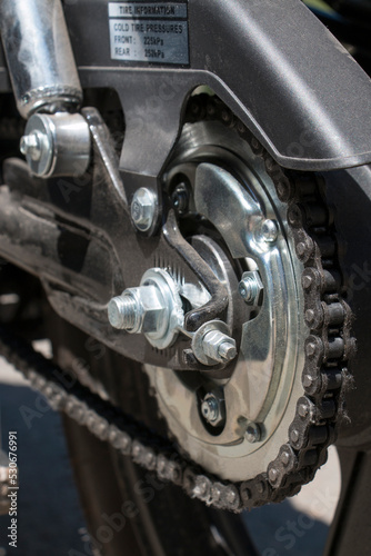 Detail of a motorcycle wheel, swingarm, sprocket and rear drive chain transmitting engine power