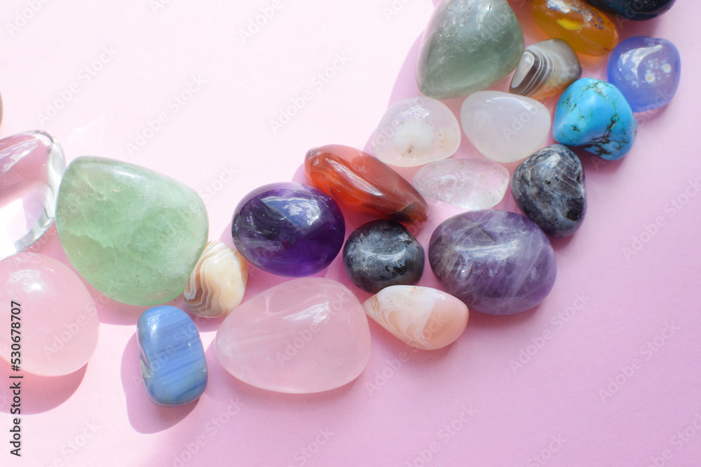 Semi-precious beautiful stones of bright colors lie on a pink background. Amethyst, rose quartz, agate, apatite, aventurine, rock crystal on a pink background. Selective focus. Semi-precious beautiful stones of bright colors lie on a pink background. Amethyst, rose quartz, agate, apatite, aventurine, rock crystal on a pink background. Selective focus.