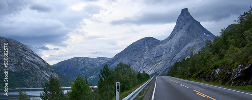 Stetind, a mountain in Norway. A tall natural granite obelisk rising directly from the fjord. Inclement weather, storm clouds in the sky. It was chosen as the national mountain of Norway.