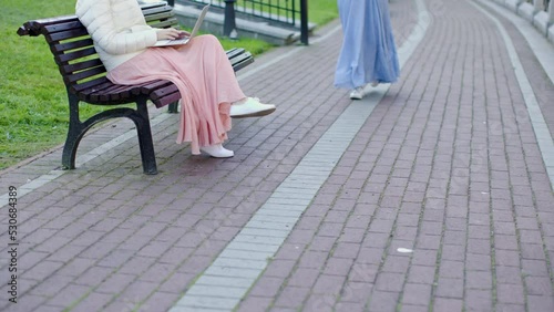 Wallpaper Mural greeting meeting two female girlfriends in city park couple woman sit on wooden bench outdoors. unrecognizable women in long skirts chatting together looking laptop city town public park Torontodigital.ca