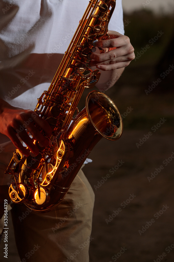 Obraz premium Hands and saxophone close up. The guy plays a wind instrument.