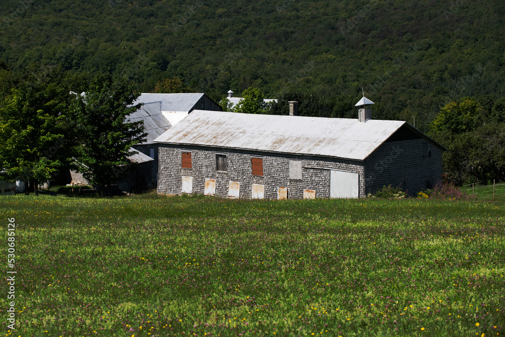 An old barn with wind turbines in the background