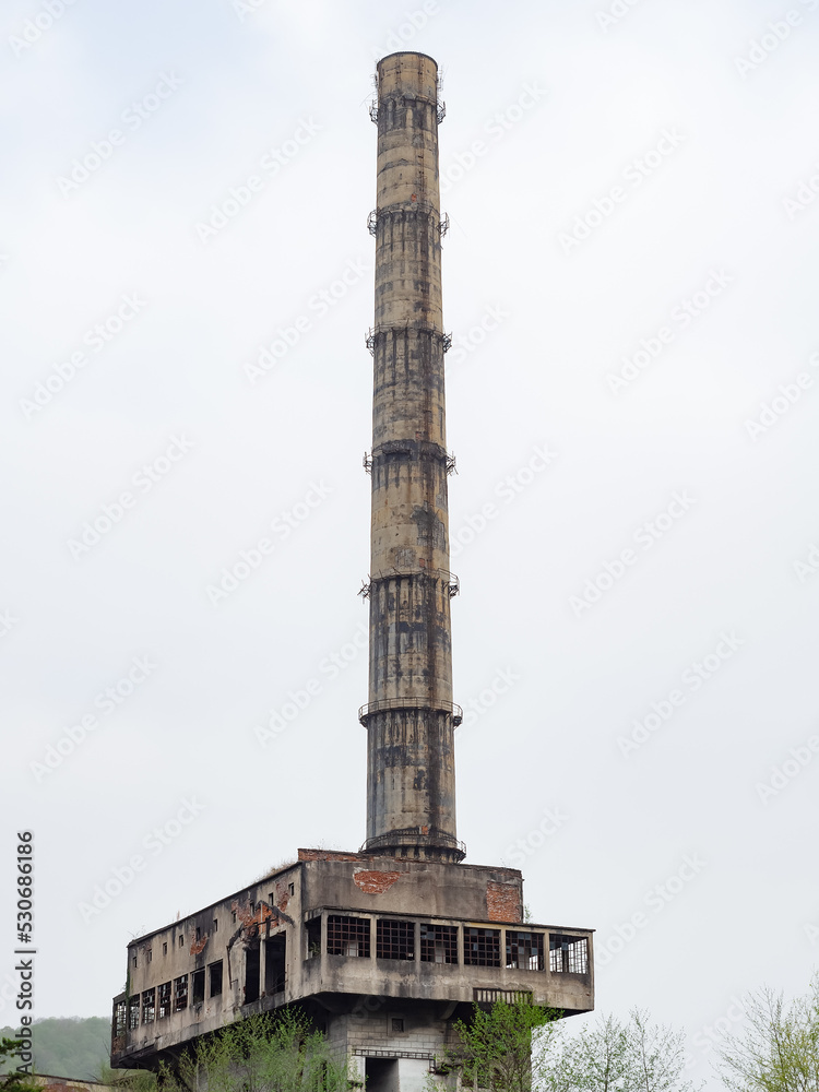 Tall chimney of an abandoned building. Abandoned building with tall chimney on a cloudy day