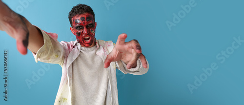 Scary zombie man on blue ba...