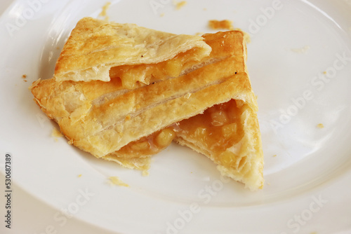 Opened Apple turnover, croissant, cake. pastry, bakery with apple cinnamon filling laying on the white plate. Close-up. Copy space.