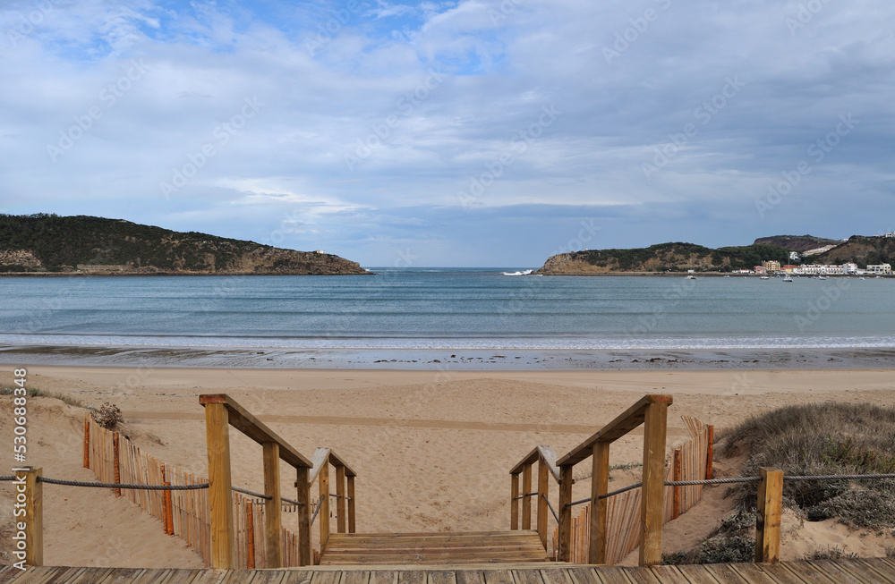 Escadas em madeira de aceso a uma praia com alinhamento com a entrada de uma enseada no mar
