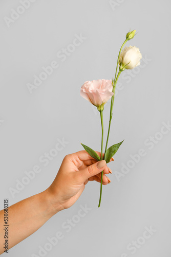 Woman with beautiful flowers on grey background