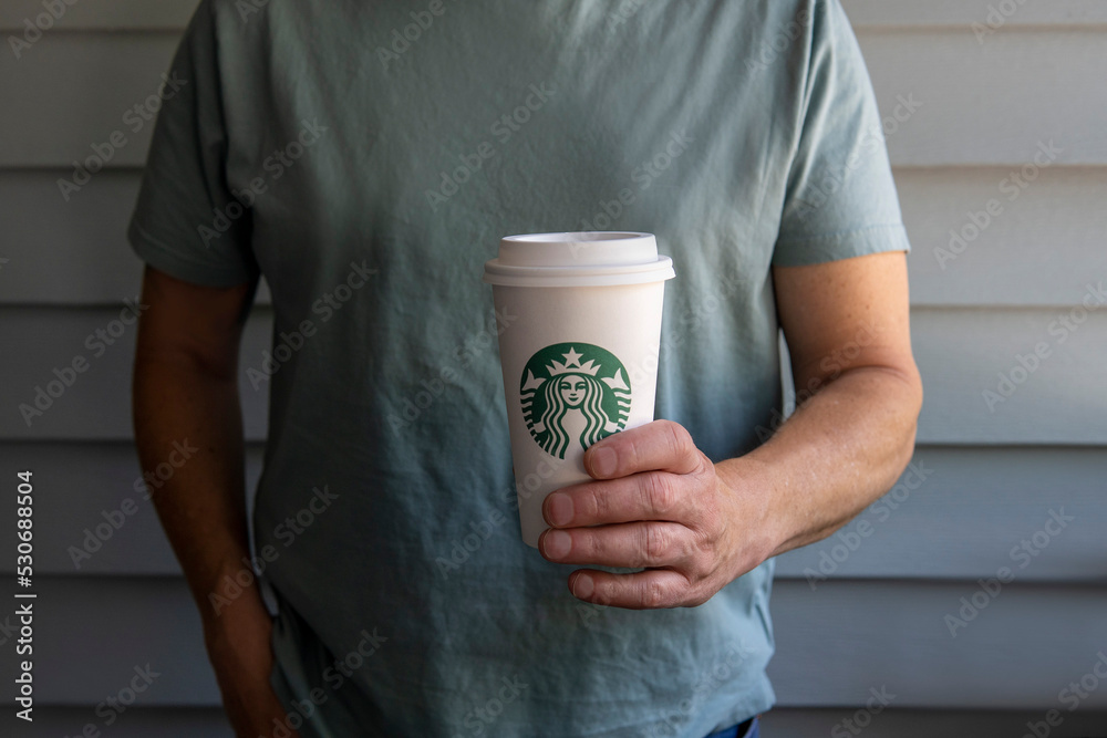 Fotka „Faceless man in a gray t-shirt holds cup of Starbucks coffee in his  hand. Prague, Czech Republic - April 2022“ ze služby Stock | Adobe Stock