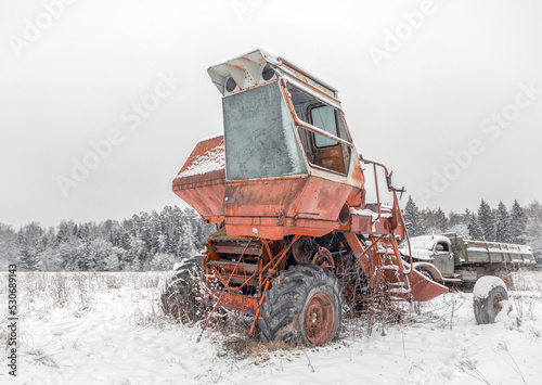 Red broken frozen combine harvester on a snow-covered field.
