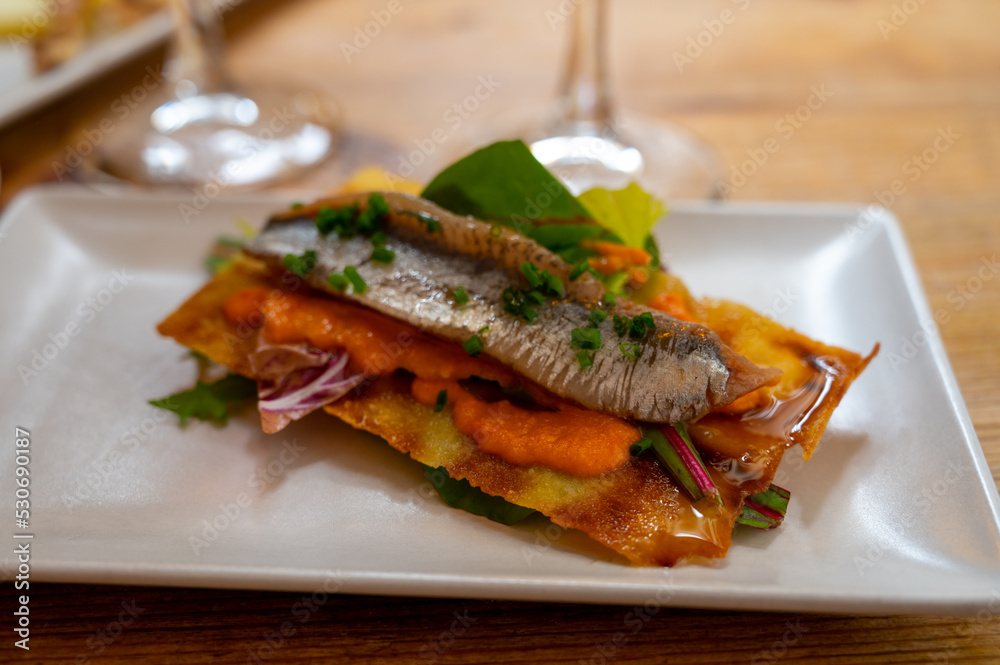 Spanish food, one tapas small piece of roasted bread cracker with vegetables puree and smoked sardine fish Spanish food, one tapas small piece of roasted bread cracker with vegetables puree and smoked sardine fish