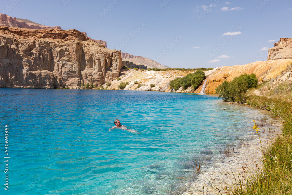 Western man swimming in a lake and enjoying cristal clear blue water of Band-e Amir National Park, one of the main tourist attractions in Afghanistan