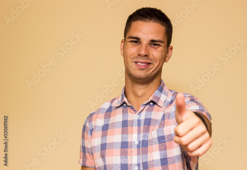 Handsome young man gesturing Thumbs Up