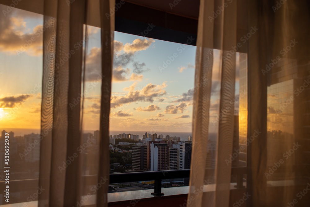 sunset seen from apartment window with curtains