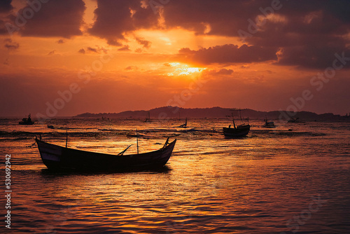 Beautiful bright sunset over the water with old wooden boats photo