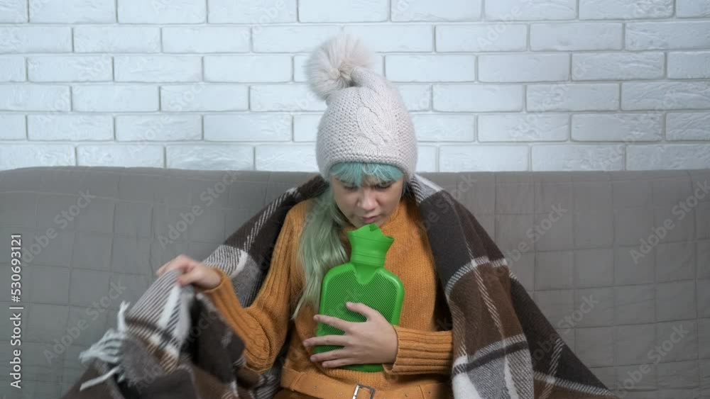Feeling uncomfortable in winter flat. A stressed teen feeling uncomfortable in winter clothes with heating pad with hot water in the room. Feeling uncomfortable in winter flat. A stressed teen feeling uncomfortable in winter clothes with heating pad with hot water in the room.