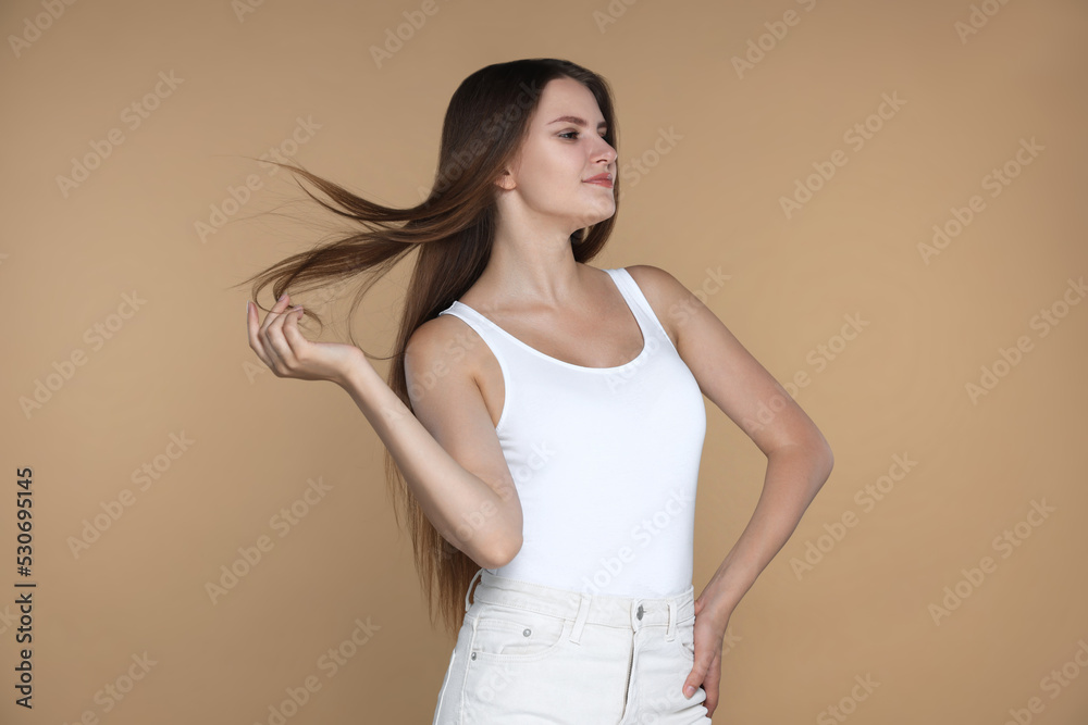 Young woman with strong healthy hair on beige background Young woman with strong healthy hair on beige background