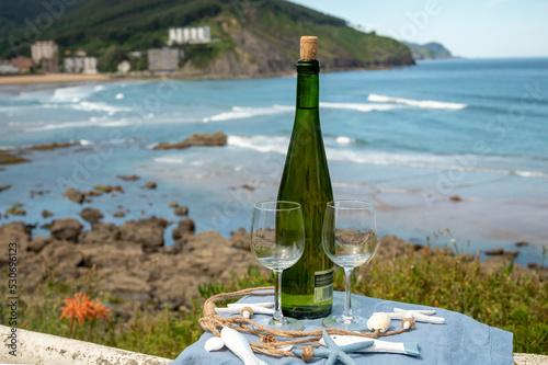 Tasting of txakoli or chacolí slightly sparkling very dry white wine produced in the Spanish Basque Country, served outdoor with view on Bay of Biscay, Atlantic Ocean.