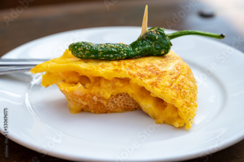 Typical snack in bars of Basque Country, pinchos or pinxtos, small slices of bread withn different toppings and fastened with skewers, San Sebastian, Spain. Potato tortilla with green pepper. photo