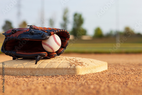 Photography Selective focus of a baseball in a leather mitt on a base of a baseball park inf