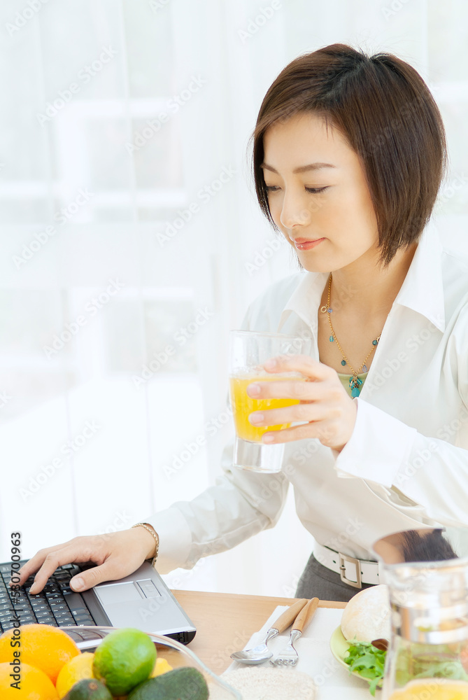 パソコンを見ながら朝食をとる女性 パソコンを見ながら朝食をとる女性