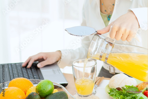 パソコンを見ながら朝食をとる女性