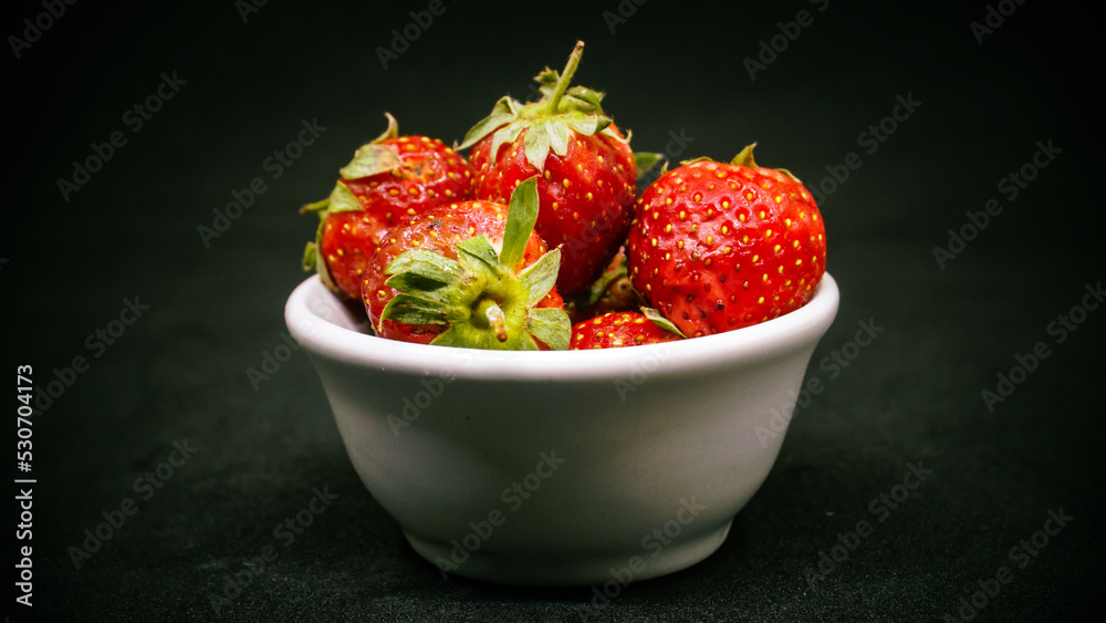 Fresh ripe delicious strawberries in a white bowl on a black background Fresh ripe delicious strawberries in a white bowl on a black background