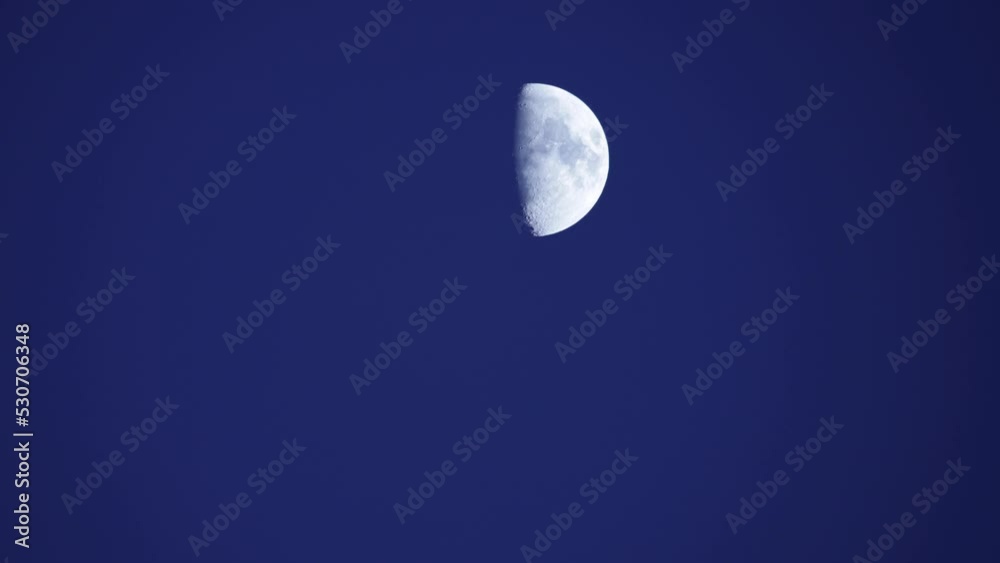 Waxing crescent half moon moving over clear blue sky background in evening. Waxing crescent half moon moving over clear blue sky background in evening.