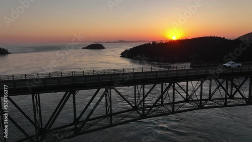 Aerial shot of a white truck driving over Deception Pass State Park at sunset. photo