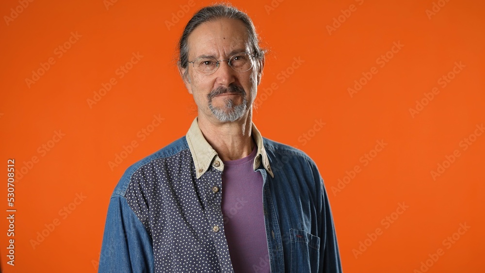 Fototapeta premium Happy bearded man 50s look camera smiling isolated on sold orange background studio portrait. People emotions lifestyle concept