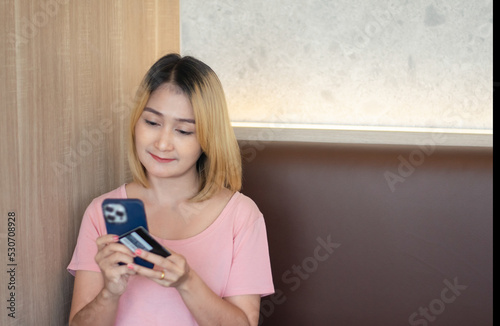 woman holding mobile phones online to purchase shopping using credit cards to pay order code discounts by payment website at home photo