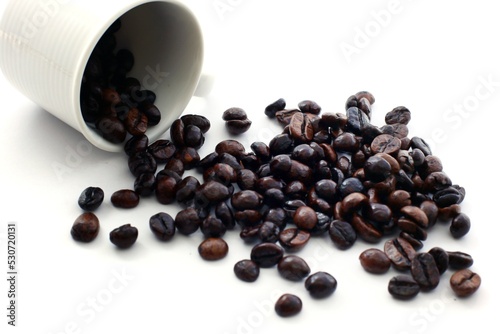 Coffee beans outpour a cup on a white background photo