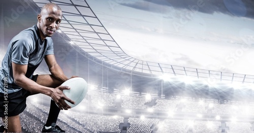 Composition of male rugby player holding rugby ball over sports stadium