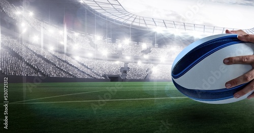 Composition of male rugby player holding rugby ball over sports stadium © vectorfusionart