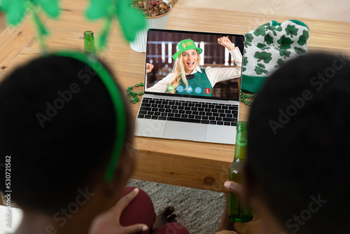 African american couple making st patrick's day video call to female friend on laptop at home