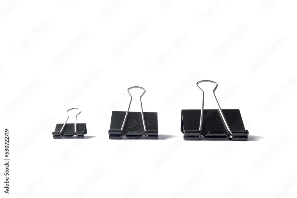 Three black binder clips of various sizes used to staple documents against
