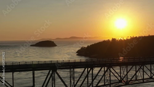 Tight aerial view of Deception Pass at sunset with a lone motorcycle riding over it. photo