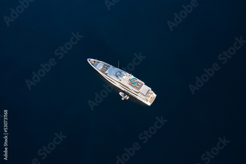 White mega yacht at anchor aerial view. Large yacht on dark blue water top view. © Berg