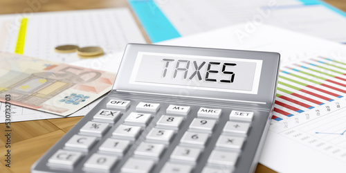 Taxes word on calculator display. Euro money and business reports on office desk